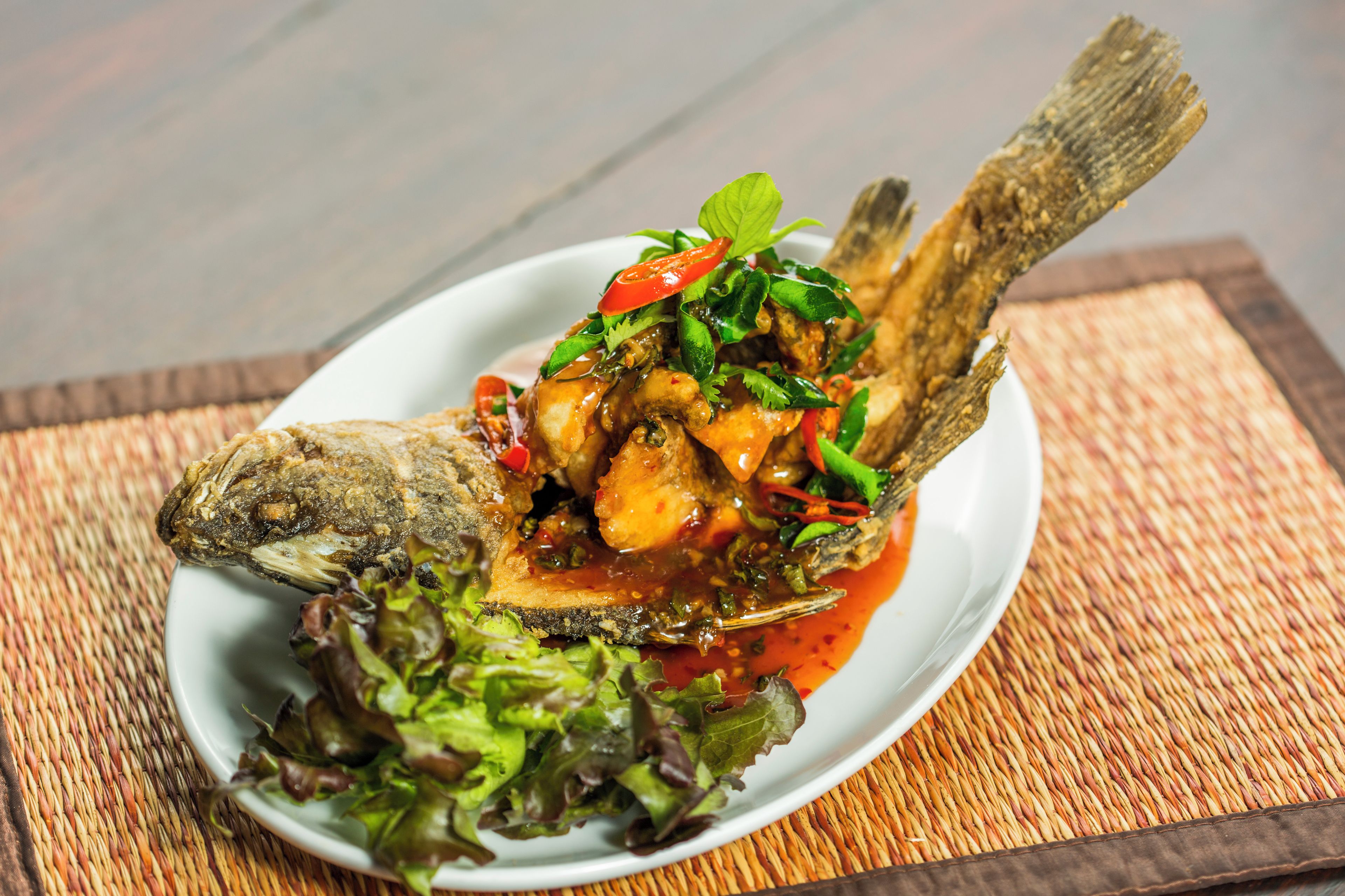 Un plato de comida con pescado, verduras y salsa.