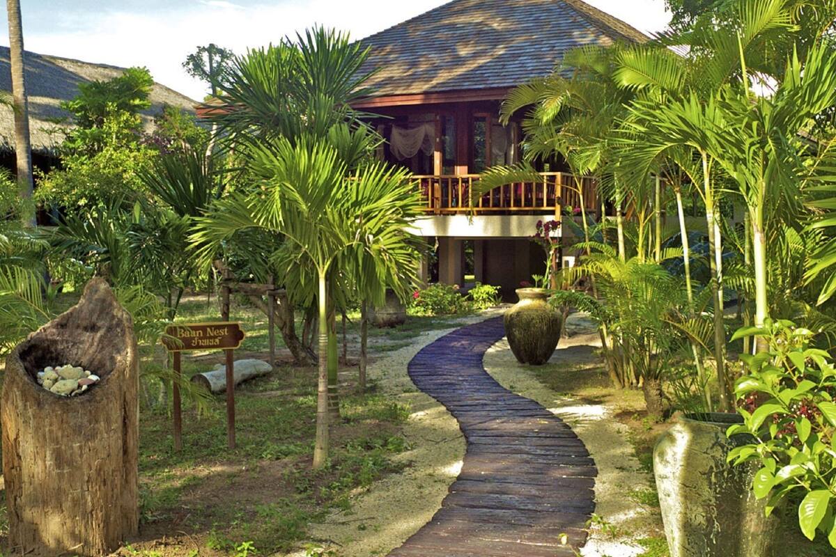 Un complexe hôtelier tropical doté d’une passerelle en bois menant à un bâtiment avec un balcon.
