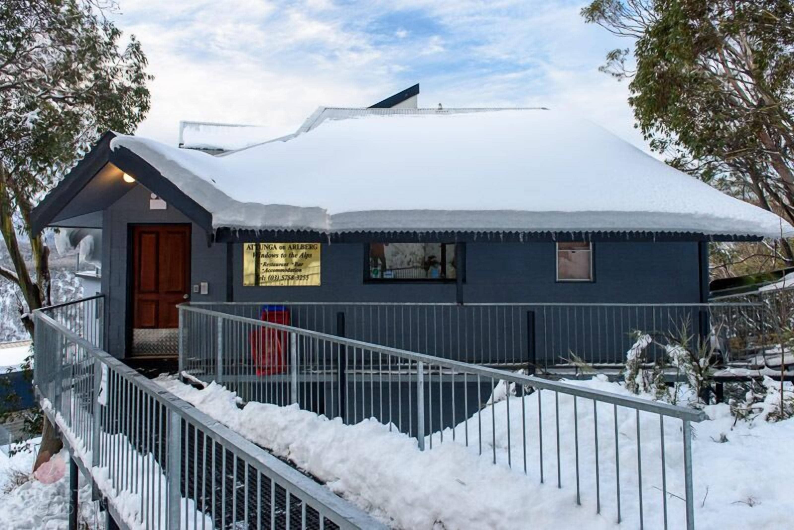Et snedækket hus med en trædør og et skilt.