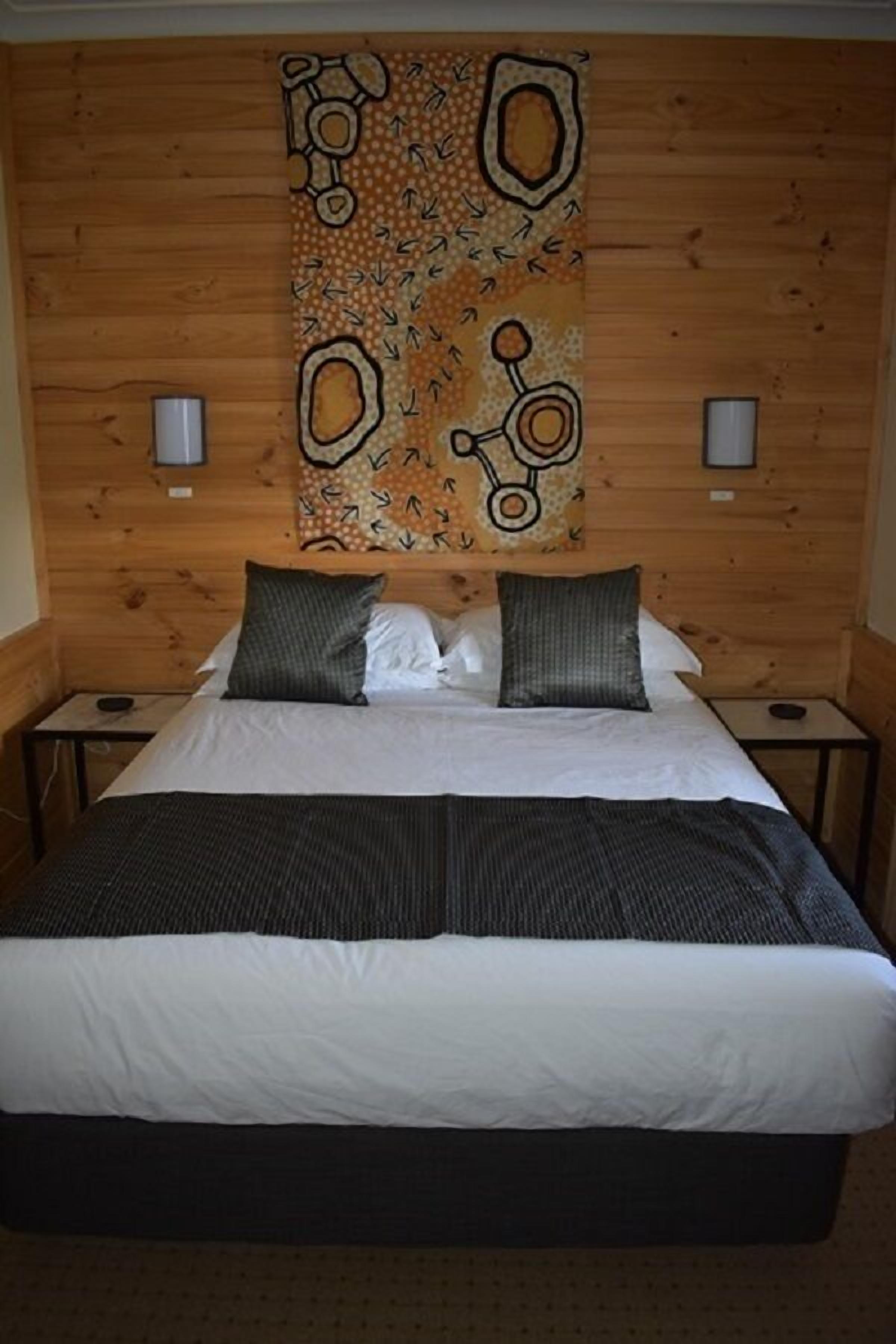 Una habitación con paneles de madera, una cama, dos mesitas de noche y un tapiz en la pared.