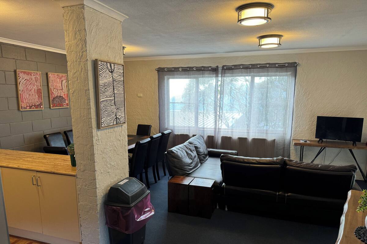 A compact living space with a sofa, a small table, a TV, and a window with curtains.