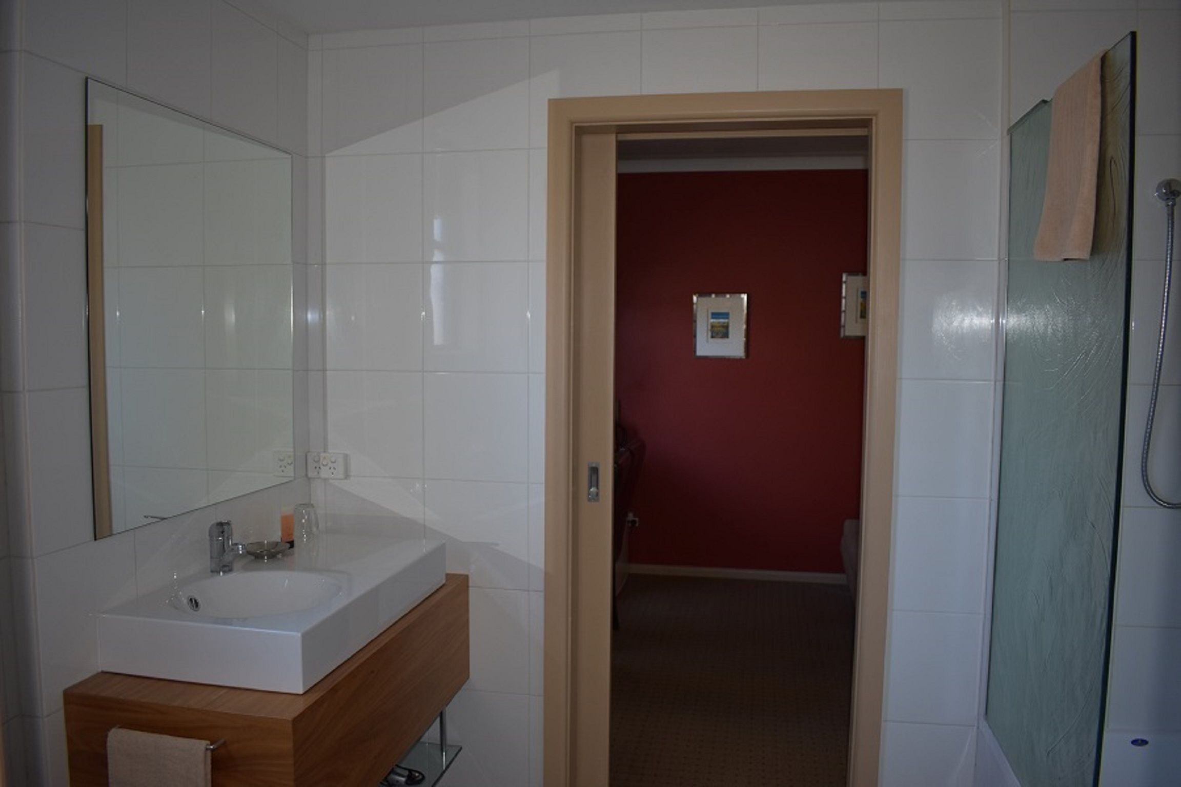 Un baño con lavamanos blanco, espejo y ducha.