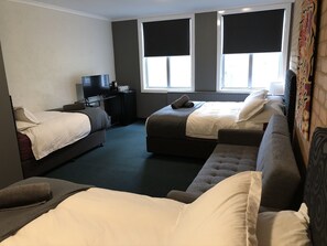 A hotel room with two single beds, a sofa, a TV, and a small table. - Attunga Alpine Lodge and Apartments (Falls Creek)
