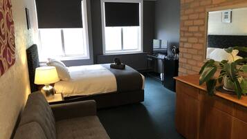 Una habitación de hotel con cama, escritorio, televisión, cafetera y una planta.
