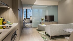 A modern hotel room with a kitchenette, a bed, a TV, and a glass partition separating the living area from the bedroom. - Capri by Fraser, Brisbane (Brisbane)