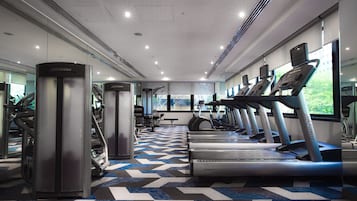 Un gimnasio moderno con máquinas de cardio, equipo de levantamiento de pesas y amplios ventanales que ofrecen luz natural.