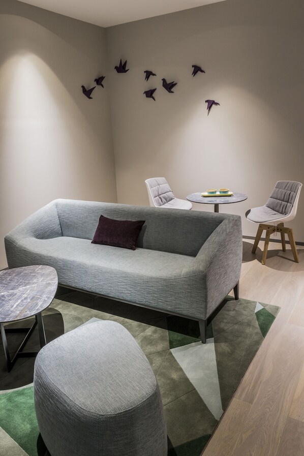 Una sala moderna con un sofá gris, dos sillones, una mesita redonda y una mesa de centro.
