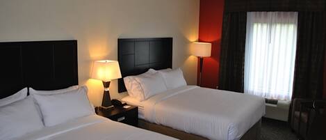 Habitación de hotel con dos camas, lámparas de noche, mesitas de noche, una ventana con cortinas y vistas al exterior.