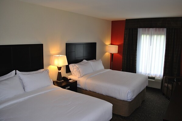 Habitación de hotel con dos camas, lámparas de noche, mesitas de noche, una ventana con cortinas y vistas al exterior.