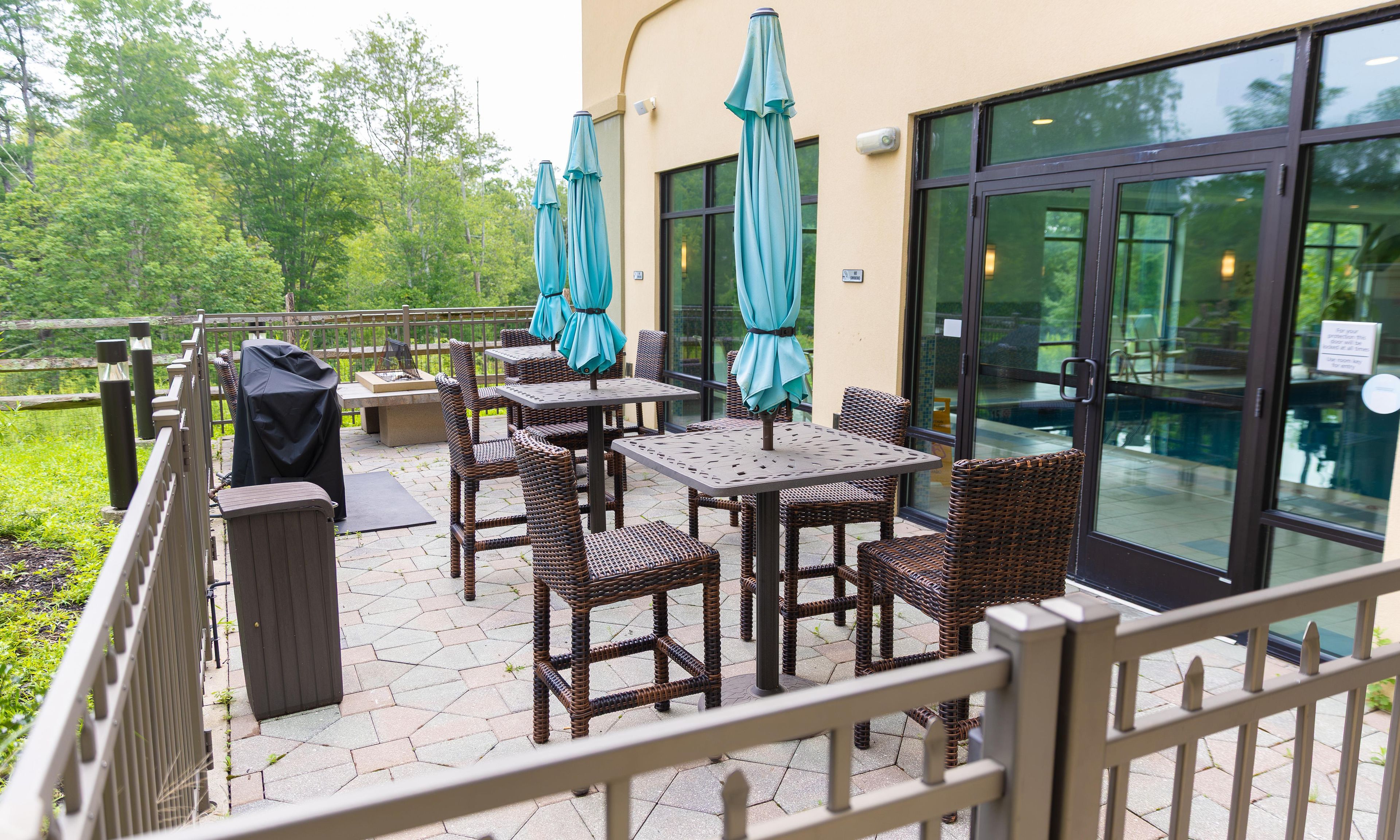 An outdoor patio with wicker furniture, umbrellas, and a grill.