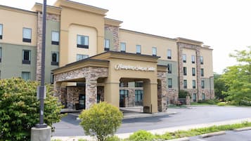 Un hotel Hampton Inn & Suites con fachada de piedra, múltiples ventanas y una entrada despejada.