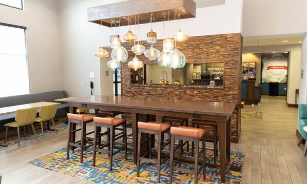 A bar area with a wooden counter, multiple stools, a patterned rug, and a mirror above the counter.