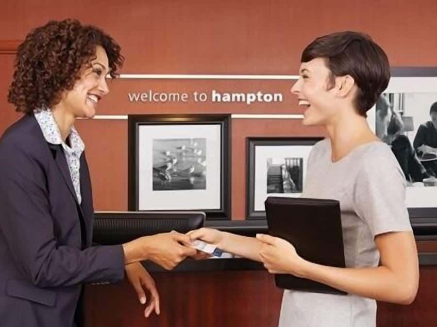 A reception desk with a sign that reads "welcome to Hampton" and framed pictures on the wall.