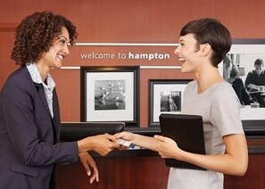 Una recepción con un letrero que dice "welcome to Hampton" y fotografías enmarcadas en la pared.