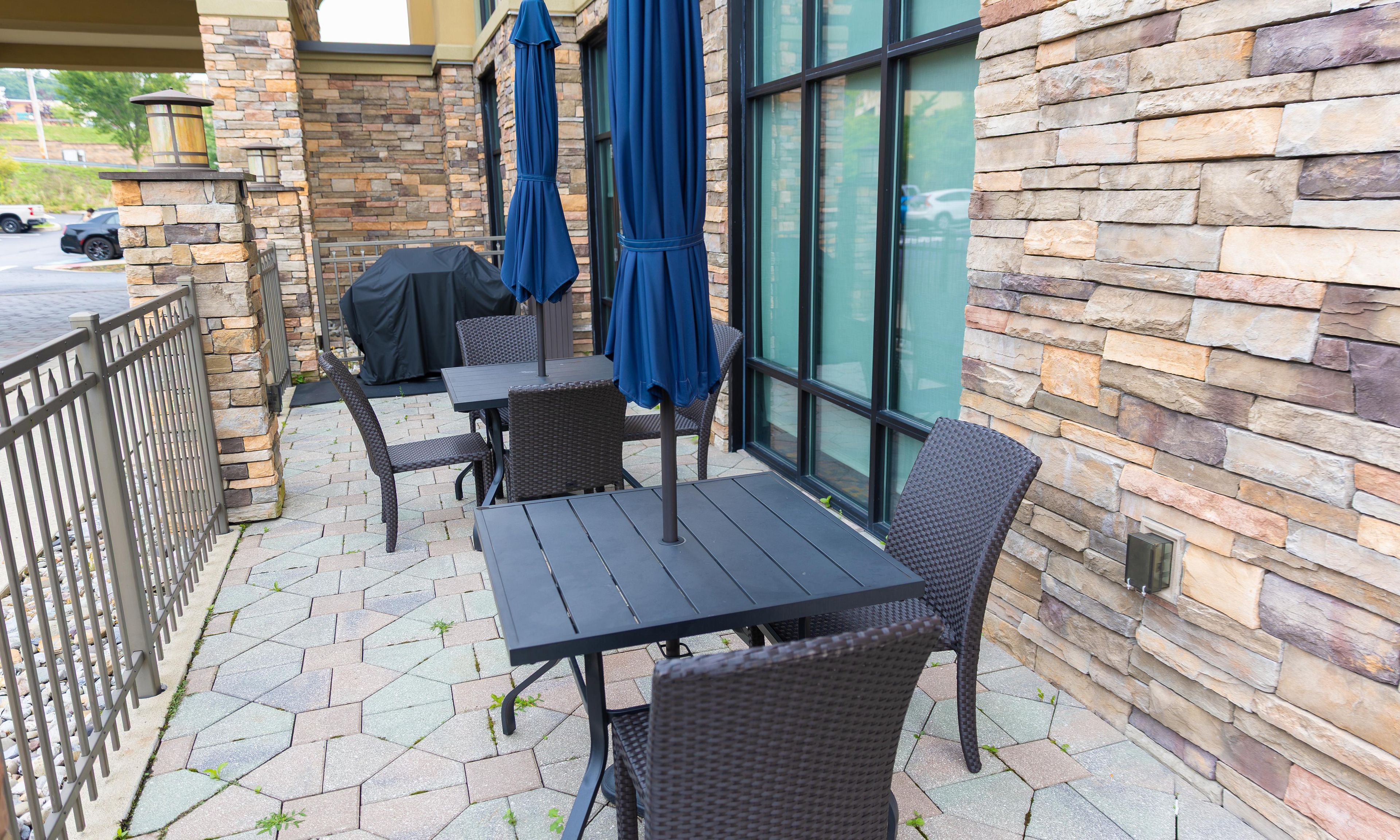 An outdoor patio with stone walls, a metal railing, and outdoor furniture.