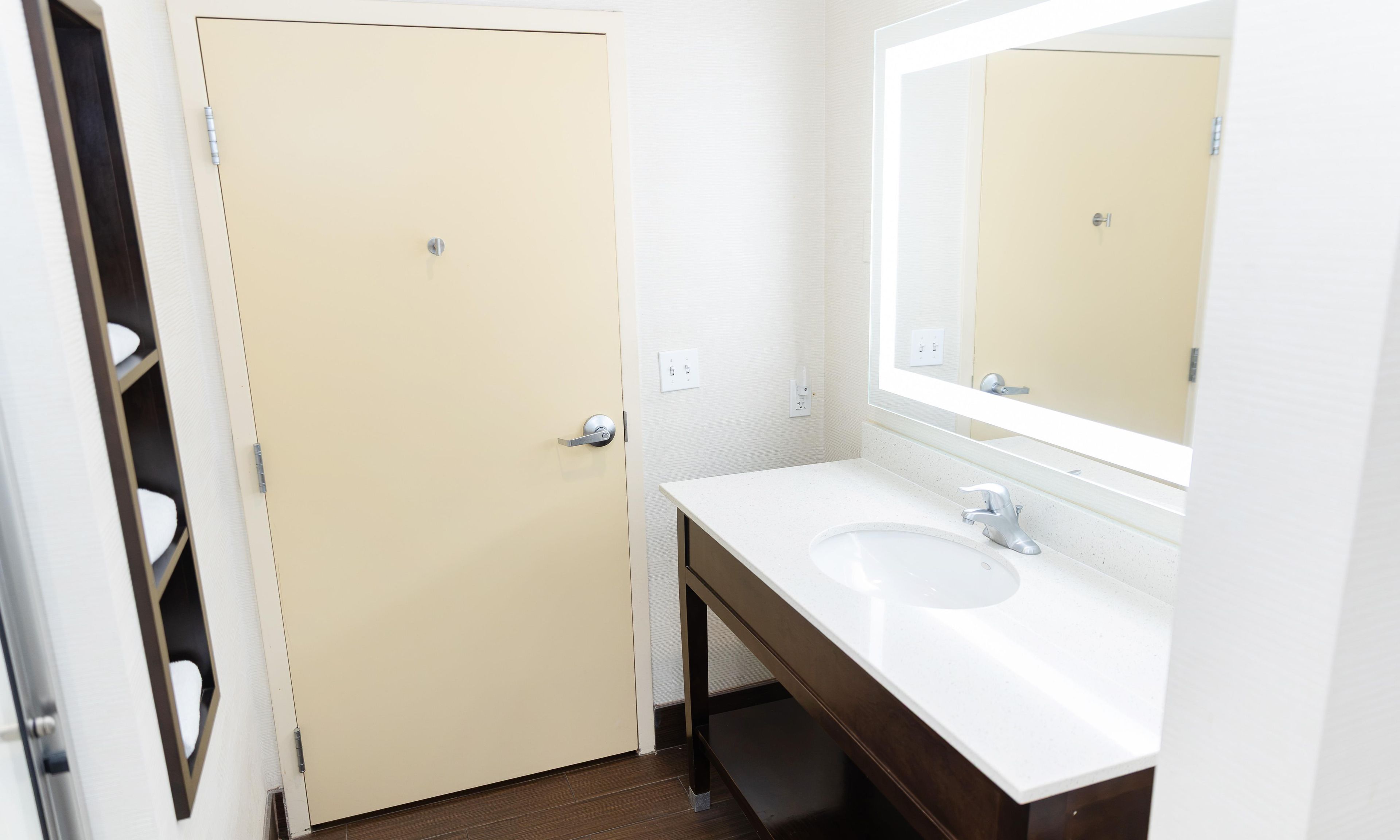A bathroom with a white sink, a mirror, and a beige door.