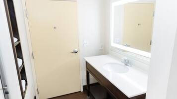 A bathroom with a white sink, a mirror, and a beige door.