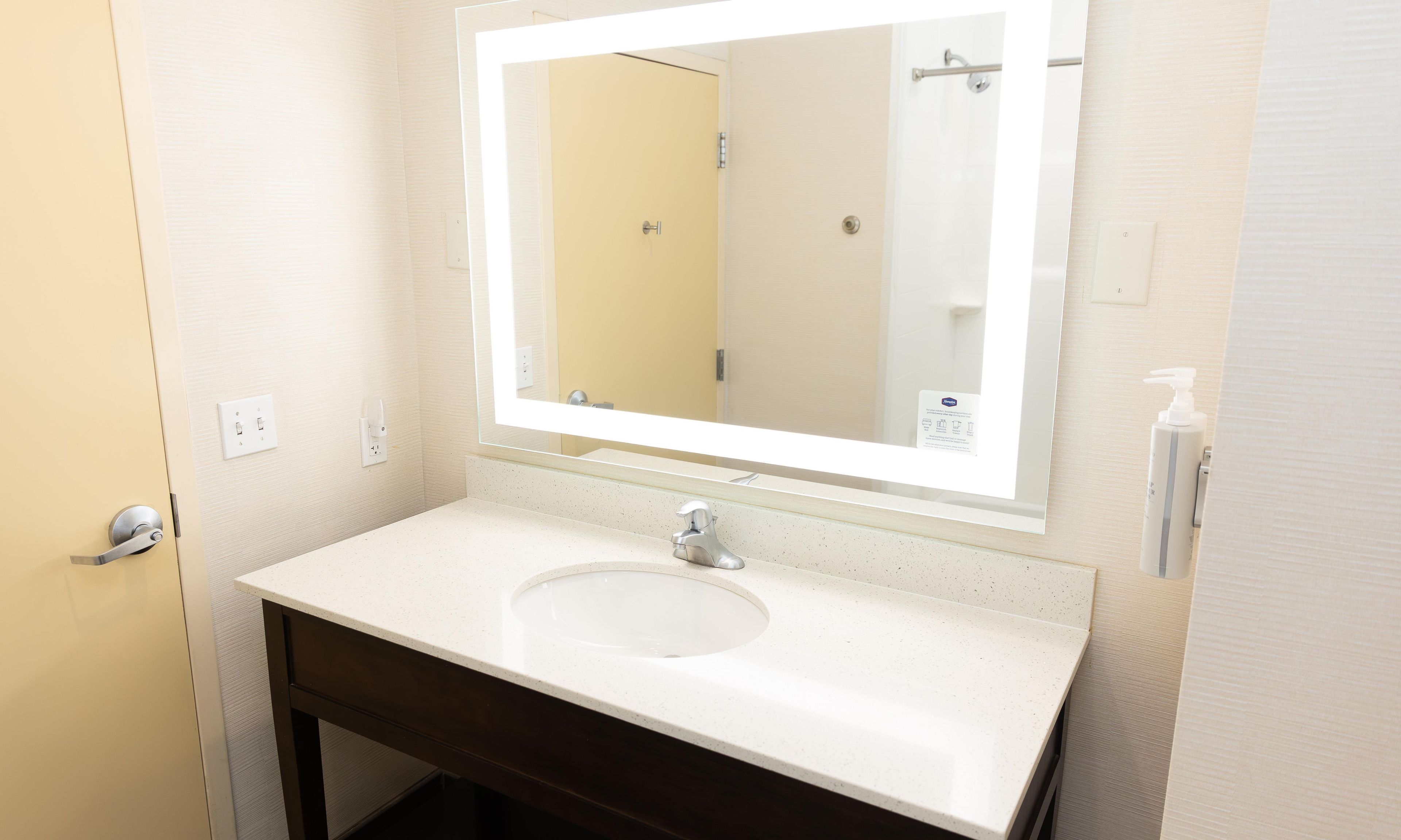 A bathroom with a white sink, a mirror, and a shower door.