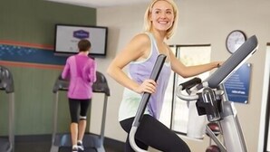 A gym with treadmills and a wall-mounted screen.