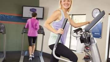 A gym with treadmills and a wall-mounted screen.