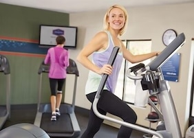 Ein Fitnessstudio mit Laufbändern und einem Bildschirm an der Wand.