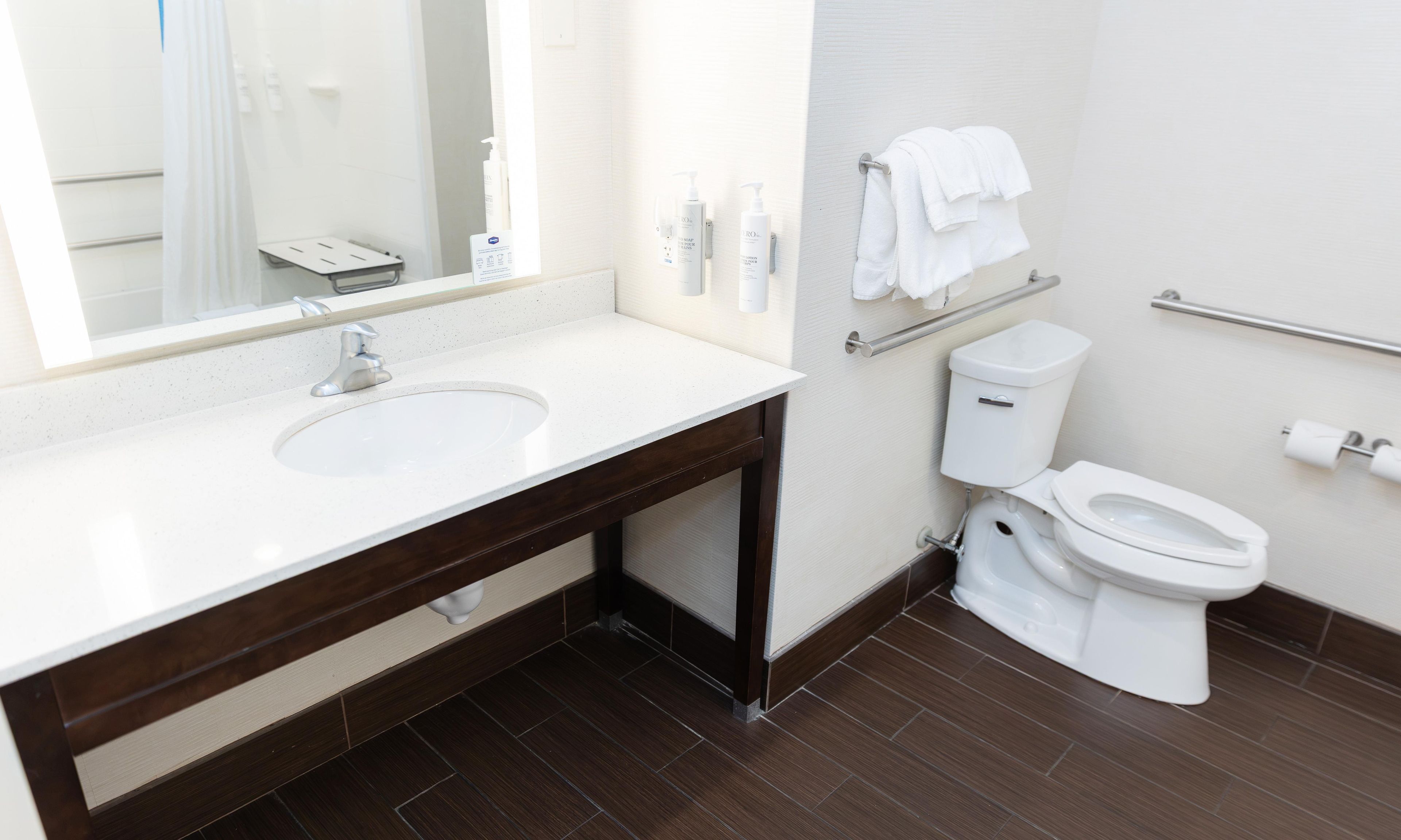 A modern bathroom with a large mirror, a sink, a toilet, and a towel rack.
