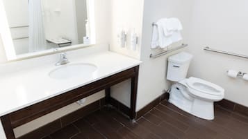 A modern bathroom with a large mirror, a sink, a toilet, and a towel rack.