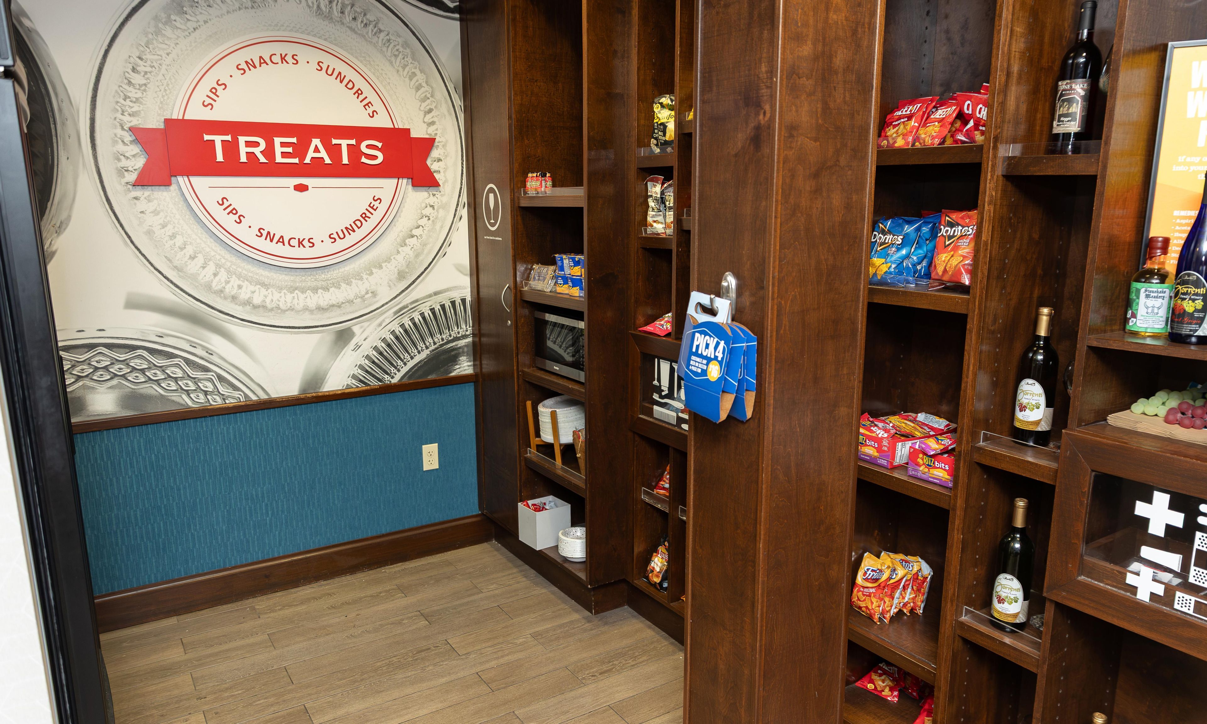 Una pared con un letrero que dice 'Treats' y estantes llenos de aperitivos y bebidas.