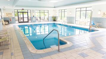 An indoor swimming pool with clear water, tiled floor, and multiple lounge chairs.