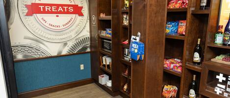 A wall with a 'Treats' sign and shelves stocked with snacks and drinks.
