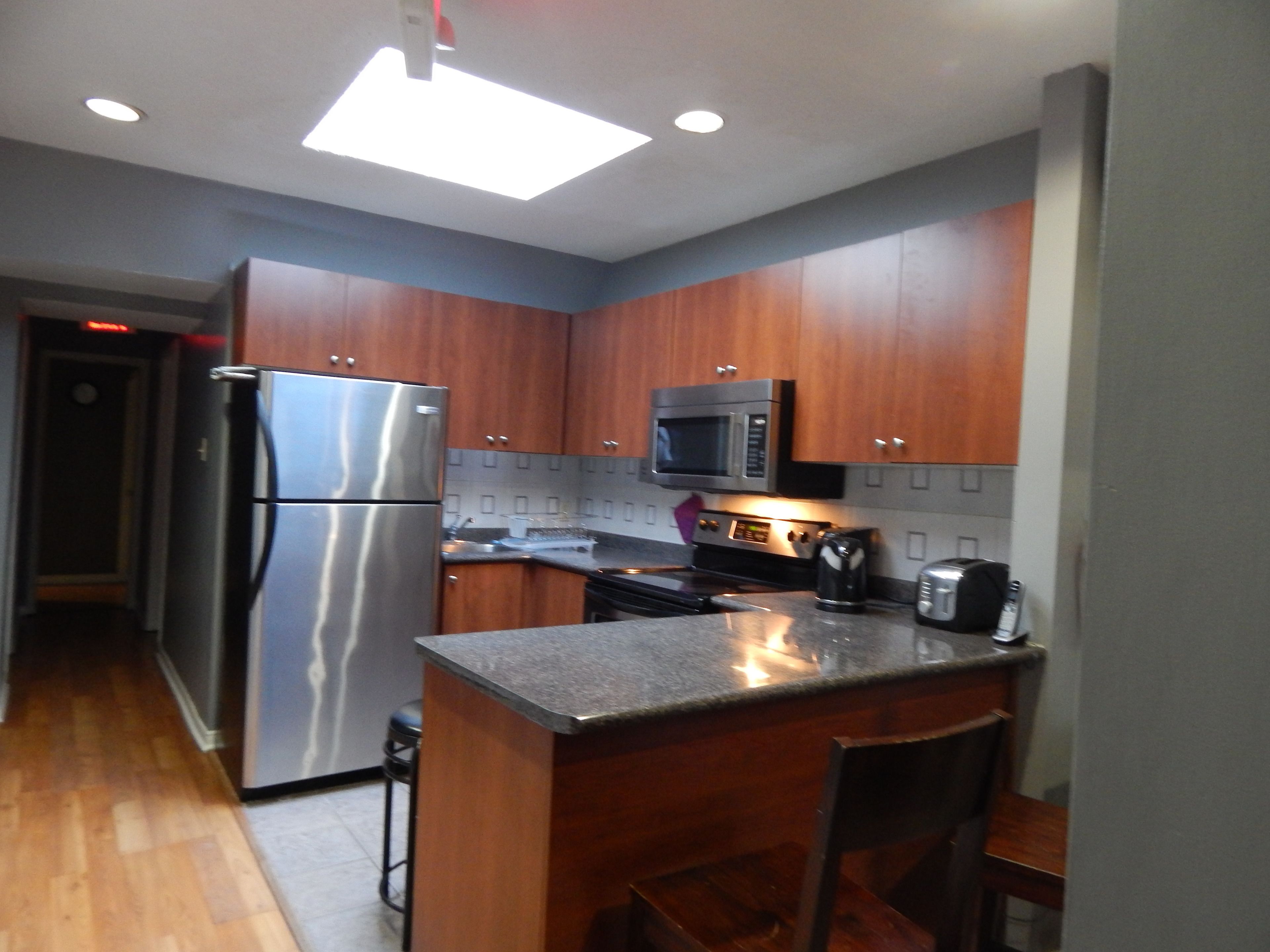 A modern kitchen with wooden cabinets, stainless steel appliances, and a bar area.