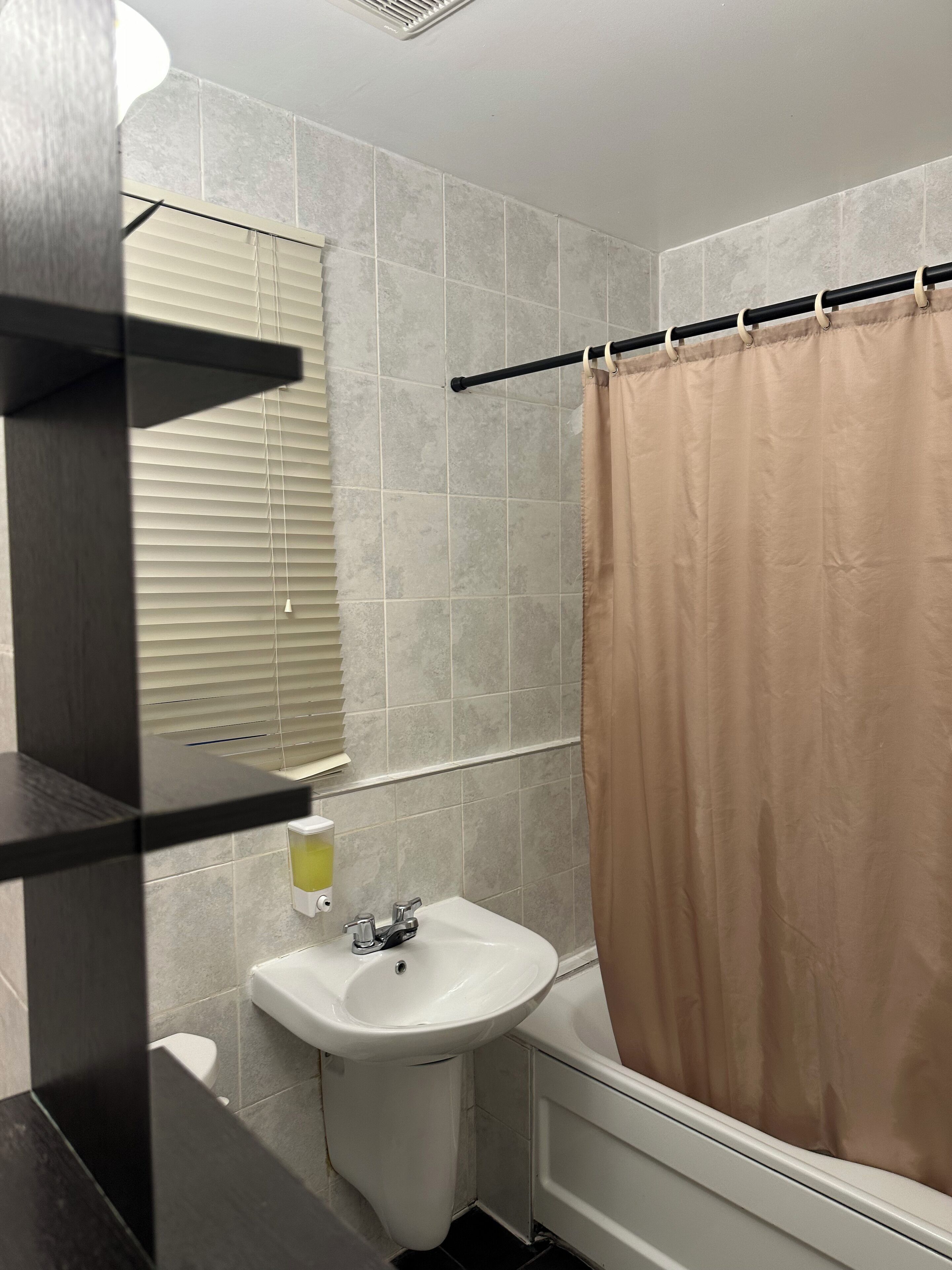 A bathroom with a white sink, a bathtub, and a beige shower curtain.