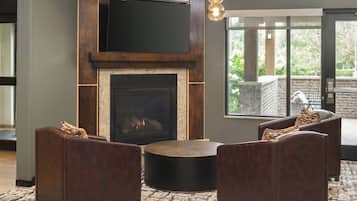 A modern living room with a fireplace, leather sofas, and a large window offering a view of the outdoors.