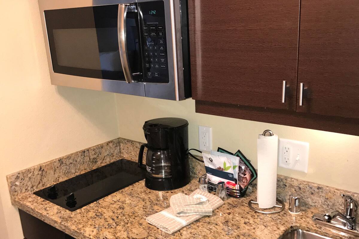 A compact kitchen with a stainless steel microwave, a coffee maker, and a dishwasher.