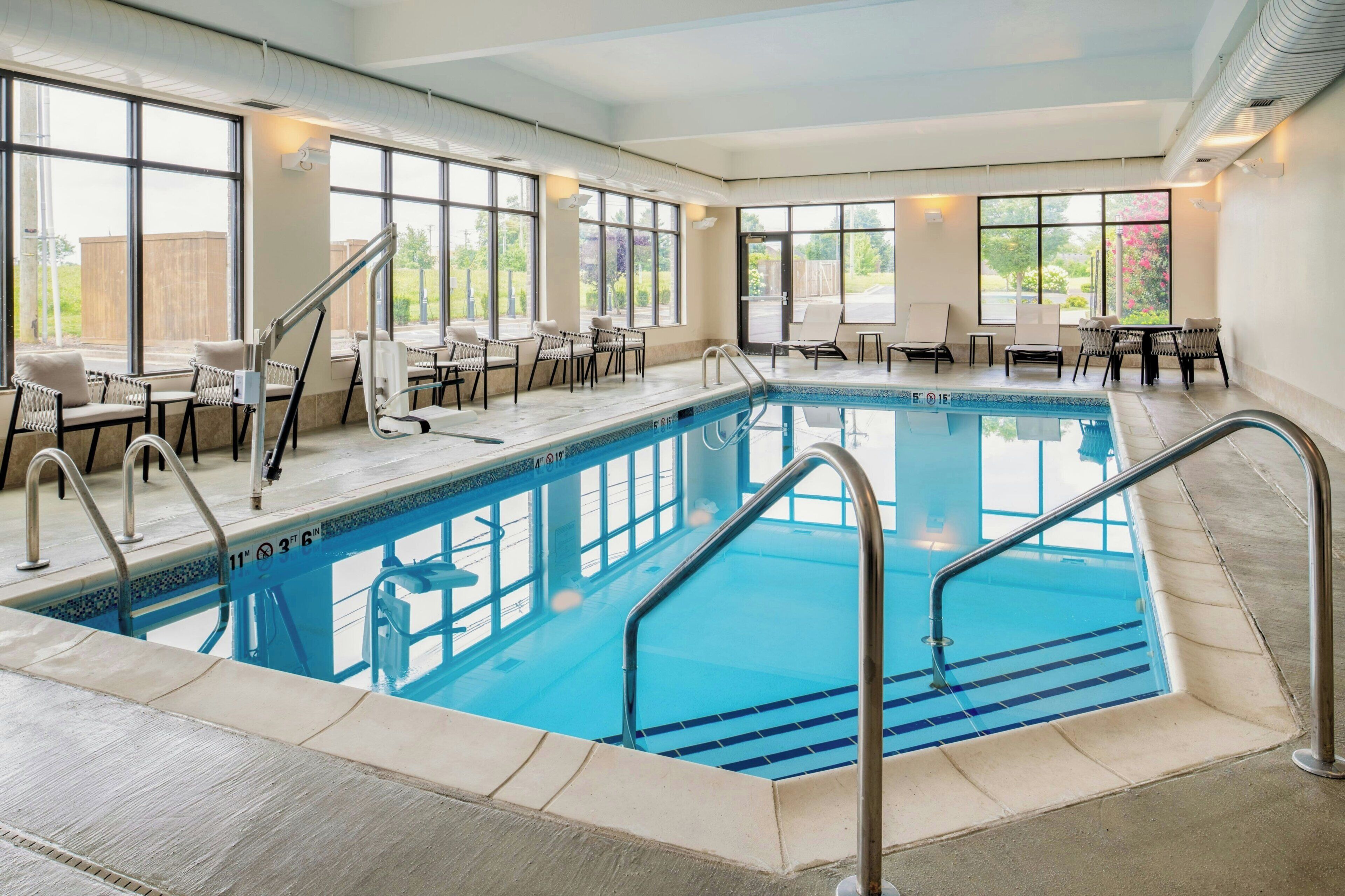 Una piscina interior con agua cristalina, rodeada de sillas de descanso y una zona de solárium.