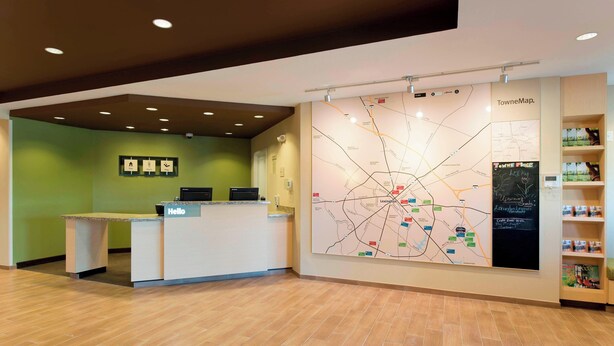 A reception area with a map, a reception desk, and a shelf with informational materials. - TownePlace Suites by Marriott Lexington South/Hamburg Place (Lexington)