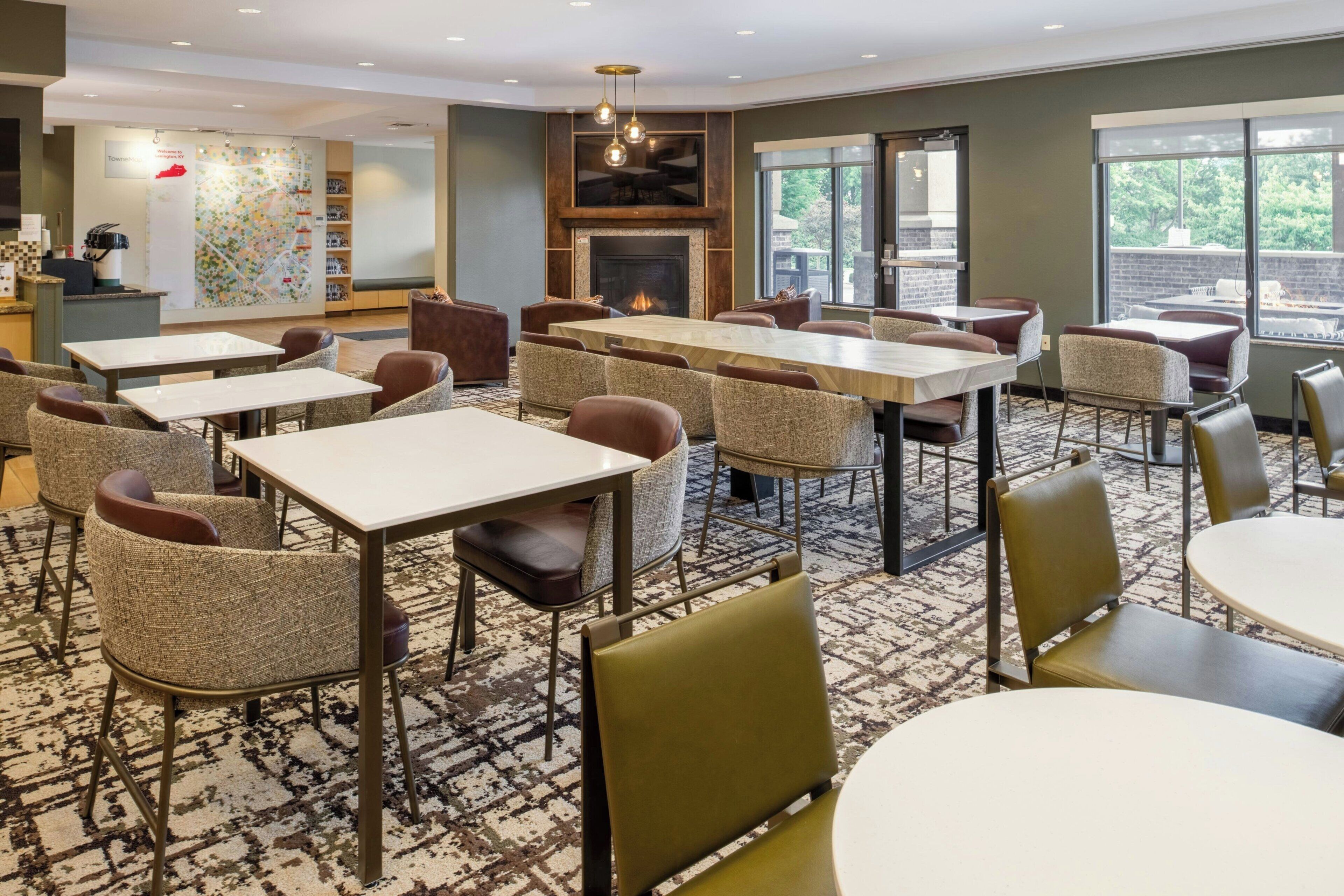A hotel lobby with multiple seating areas, a fireplace, and large windows.