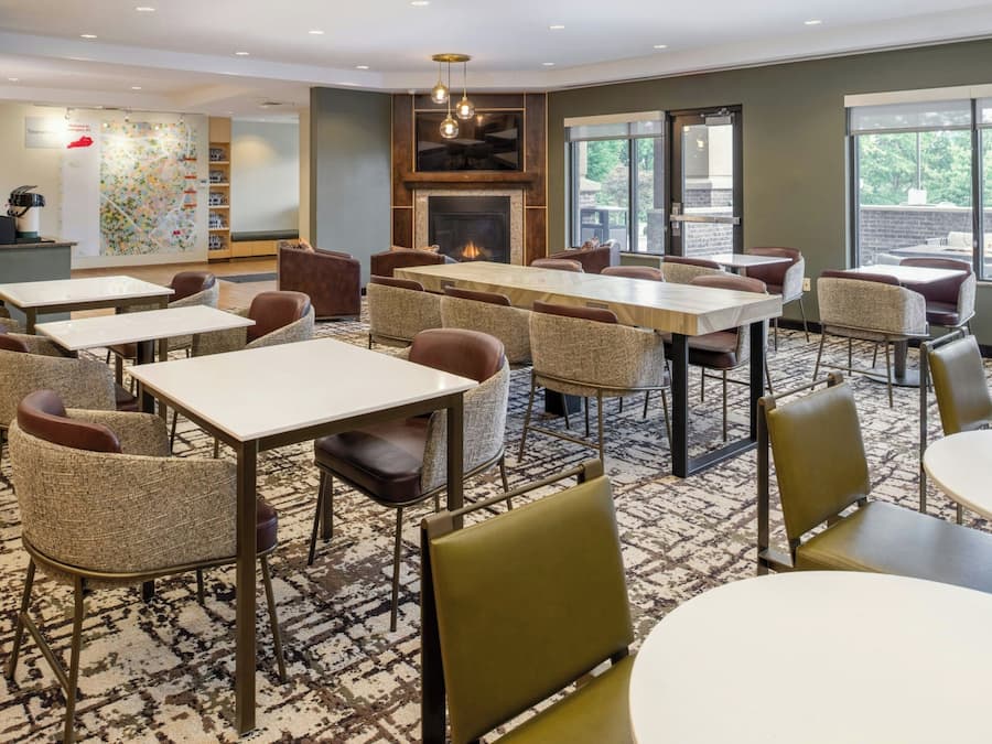 A hotel lobby with multiple seating areas, a fireplace, and large windows.