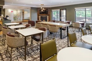 A hotel lobby with multiple seating areas, a fireplace, and large windows.