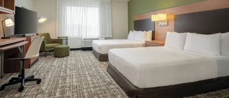 A hotel room with two beds, a desk, a chair, a television, and a window with curtains.