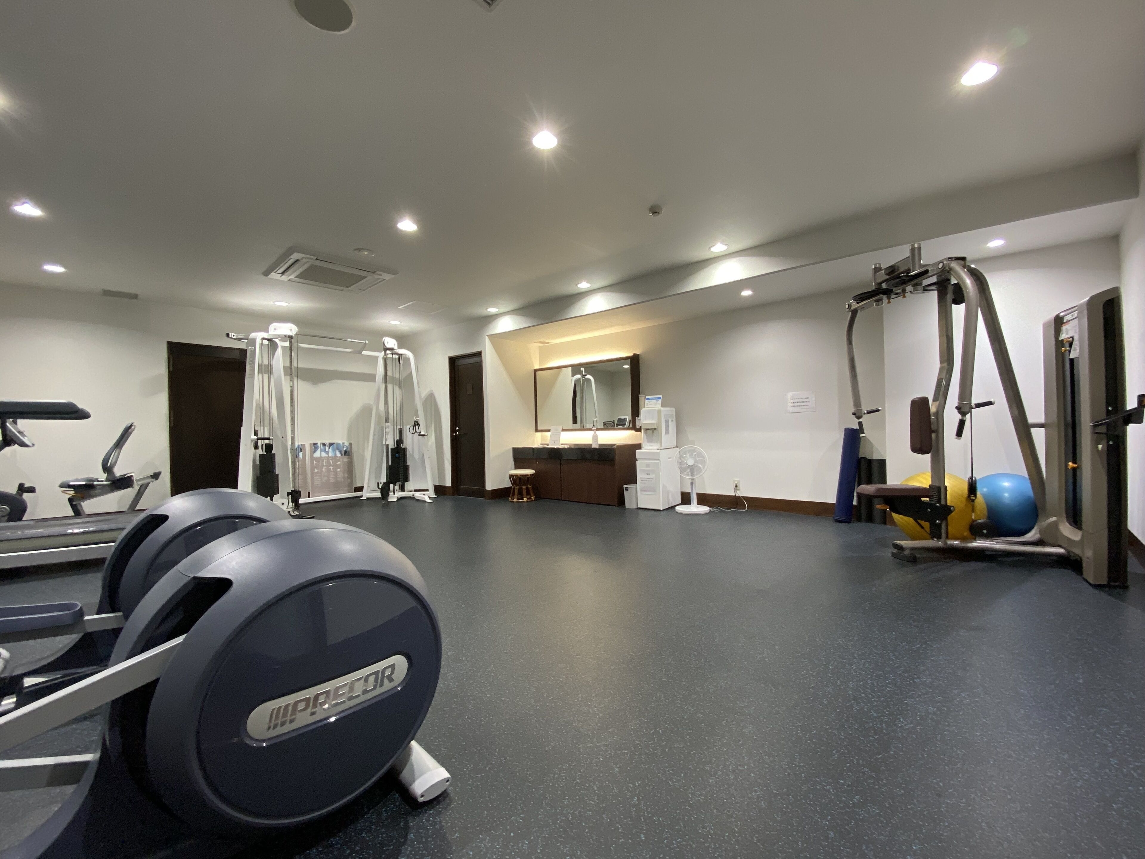 A gym with exercise equipment, a mirror, and a reception area.