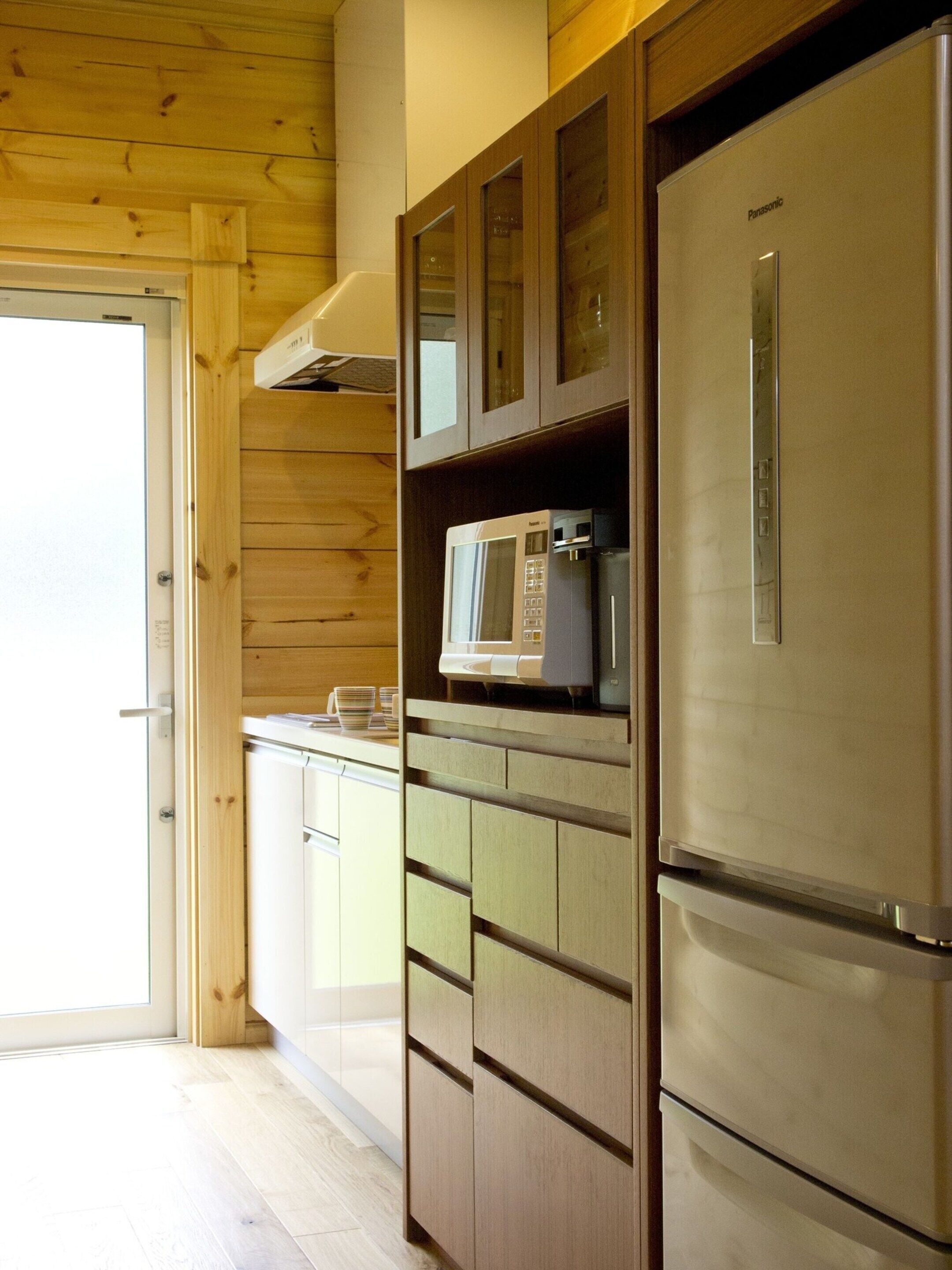 A kitchen with wooden cabinets, a microwave, and a refrigerator.