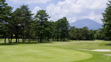 Enjoy a round of golf amidst lush trees and a scenic mountain backdrop.