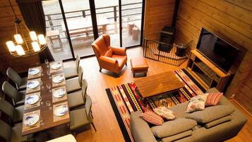 A cozy cabin interior with a dining area, sofa, and TV.