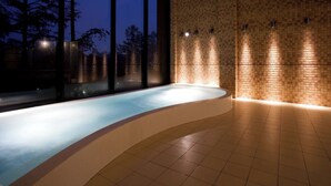 Un espacio de spa con un jacuzzi, ventanas amplias y suelo de baldosas.