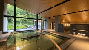 Un área de piscina interior moderna con amplios ventanales, vistas despejadas al exterior y una iluminación brillante.