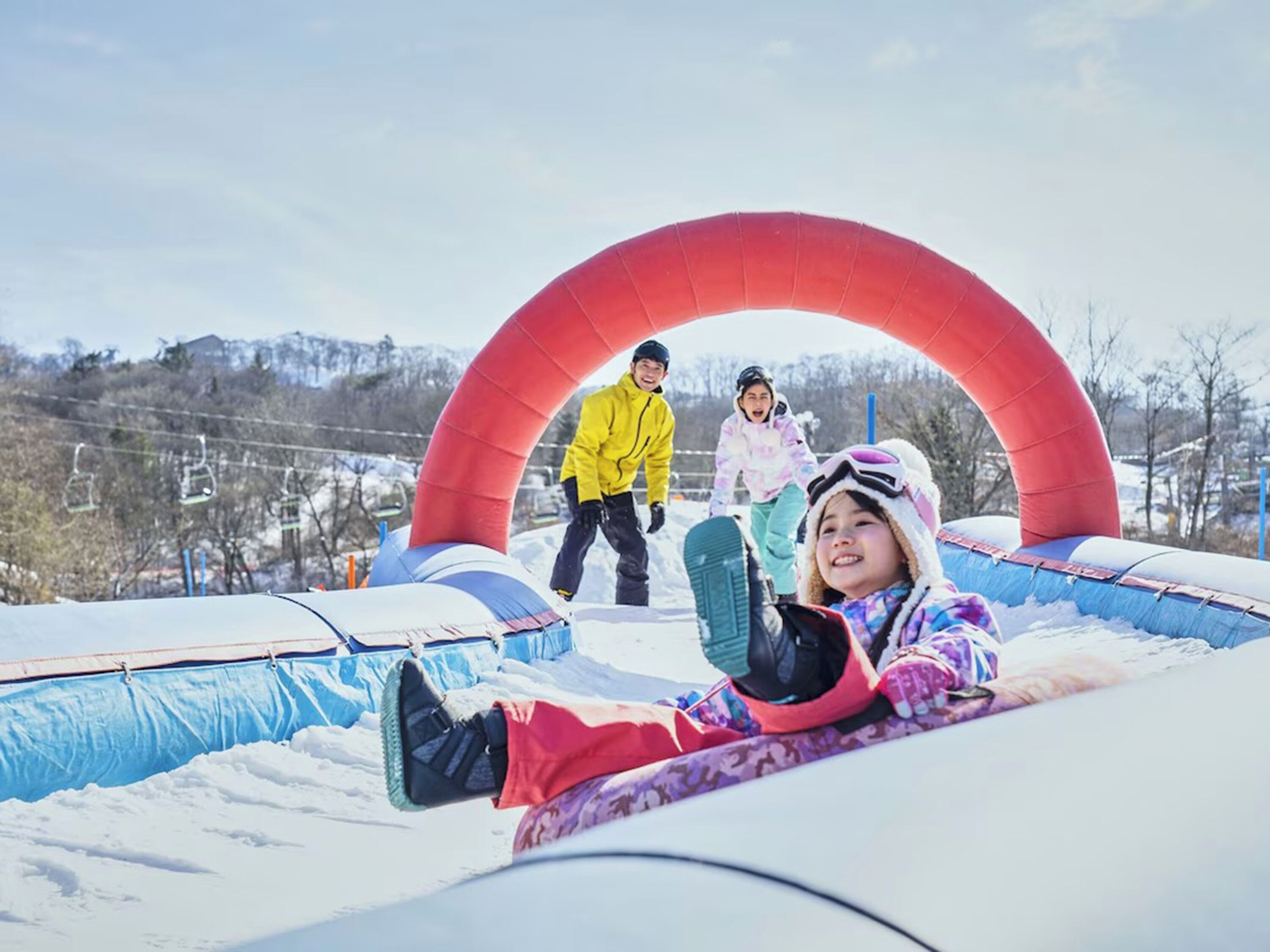 A snowy outdoor area with inflatable snow tubes and a red arch structure.