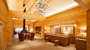 Interior de madera con mostrador de recepción, zona de estar y chimenea.