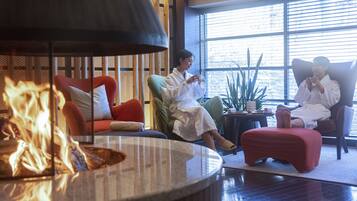 A room with a fire feature, comfortable seating, and large windows.