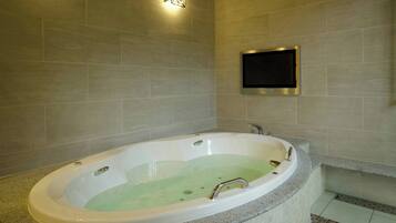 A modern bathroom with a freestanding bathtub, a wall-mounted TV, and a light fixture.